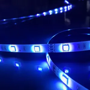 Lite Bulb Moments RGB-LED-list ihoprullad på en mörk yta, lyser blåvitt