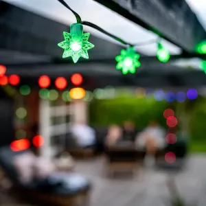 Lite Bulb Moments Smart Light Chain Stars som lyser grønt på svart ledning i et utendørs terrassemiljø