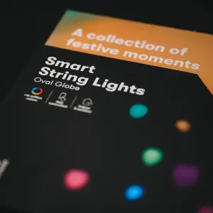Lite Bulb Moments Smart String Lights Oval Globe-förpackning med färgglad prickgrafik på en svart och orange låda