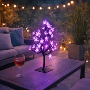 Lite Bulb Moments smarta körsbärsblomsträdslampa lyser rosa-lila på ett bord i en utomhusmiljö på en uteplats