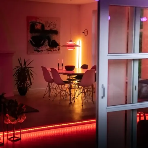 Lite Bulb Moments LED-strip monteret langs fodpanelet ved rummets åbning, lyser rødt og orange og markerer rummets kant.