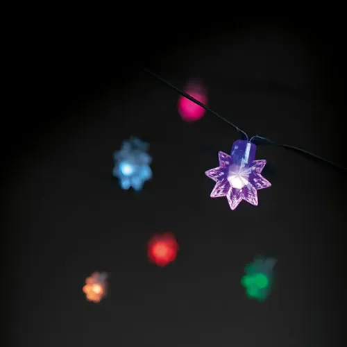 Gaismas ķēde ar zvaigznes formas LED uz melna kabeļa, tuvplāns violetai zvaigznei ar daudzkrāsainām zvaigznēm fonā.